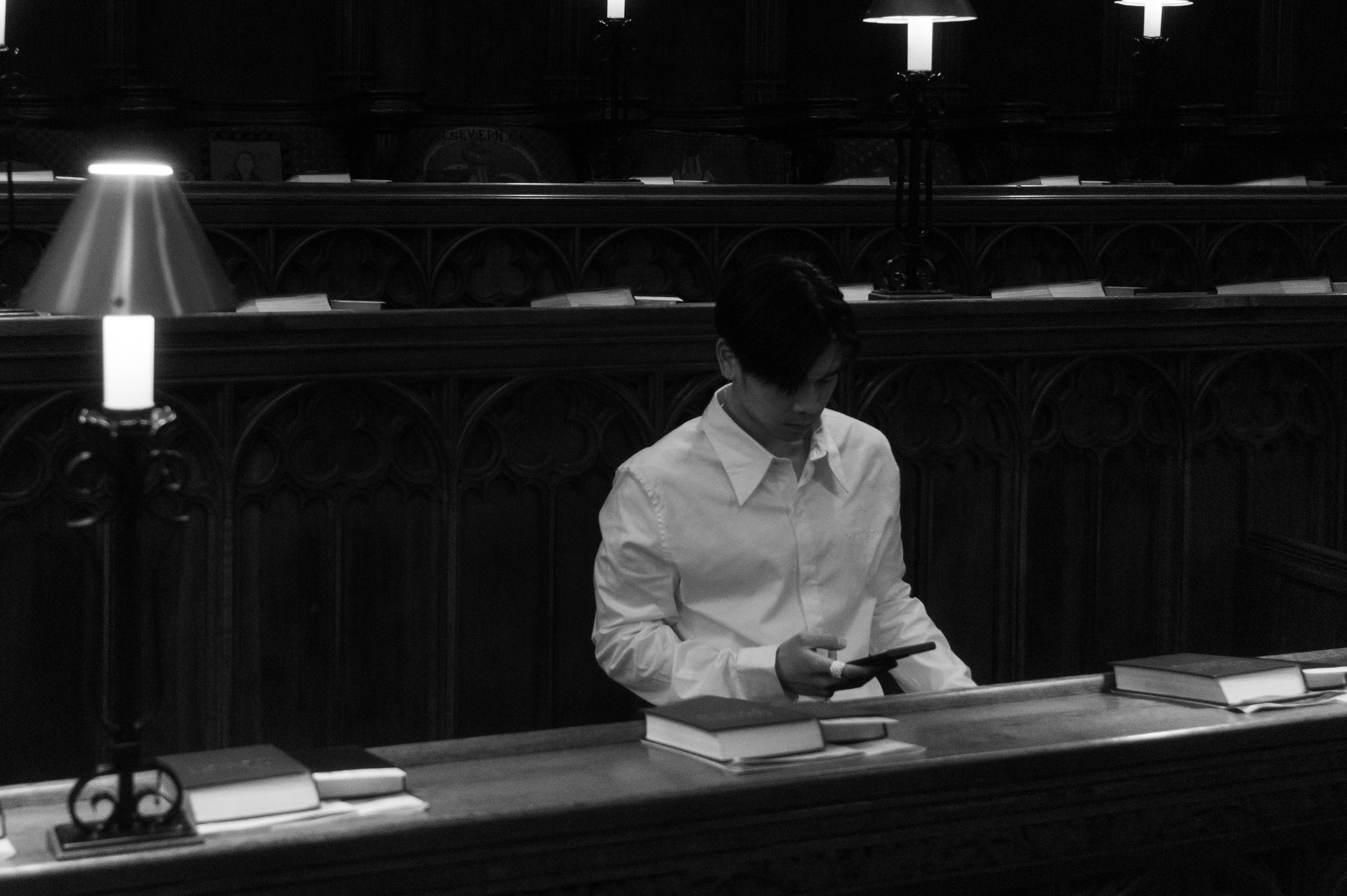 Black and white image of model sitting in courtroom seats, wearing the Regency formal shirt