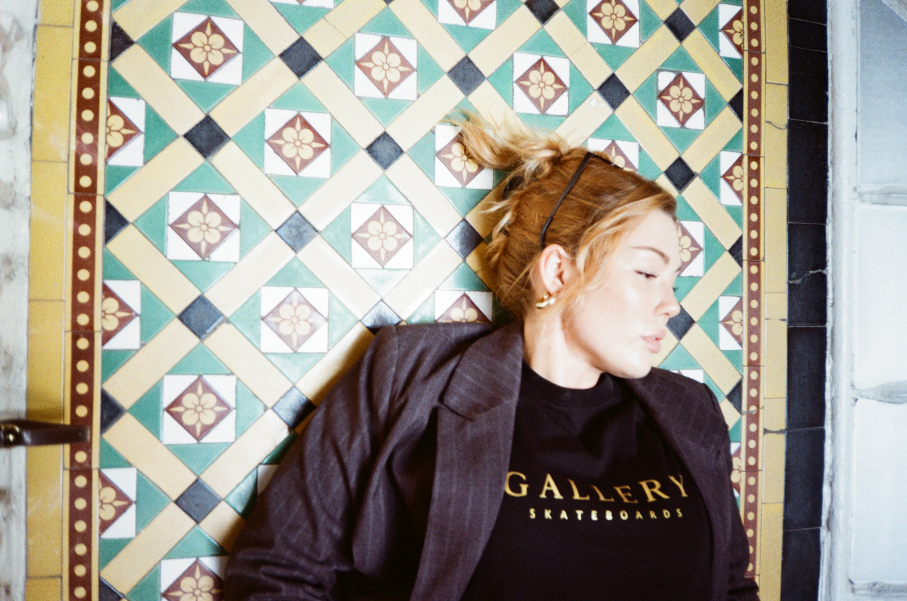 Model wearing the Monarch long sleeved tee lying on a classic patterned tiled floor, vintage style photograph.