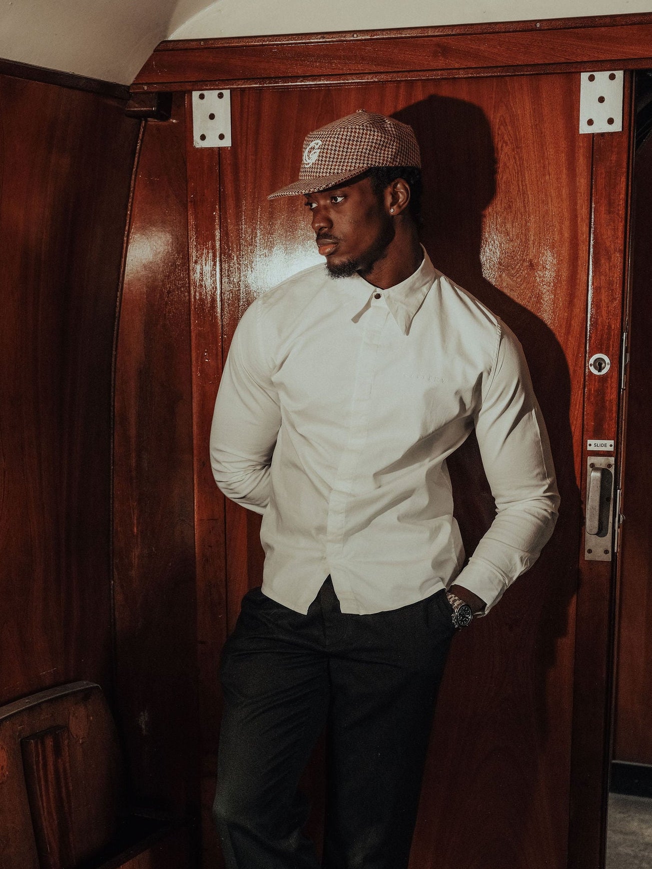 Man in a white shirt and dark pants standing in a vintage train car.