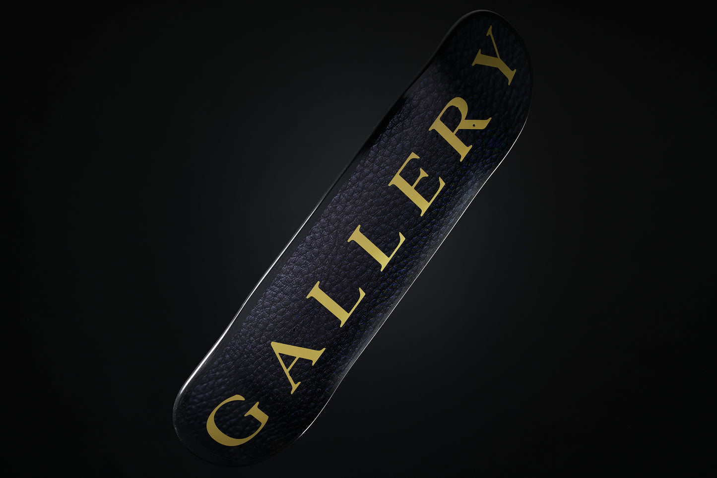 the Signature skateboard deck with black leather pattern design and large gold Gallery text logo